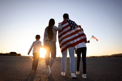 Family with flags of USA outdoors, back view