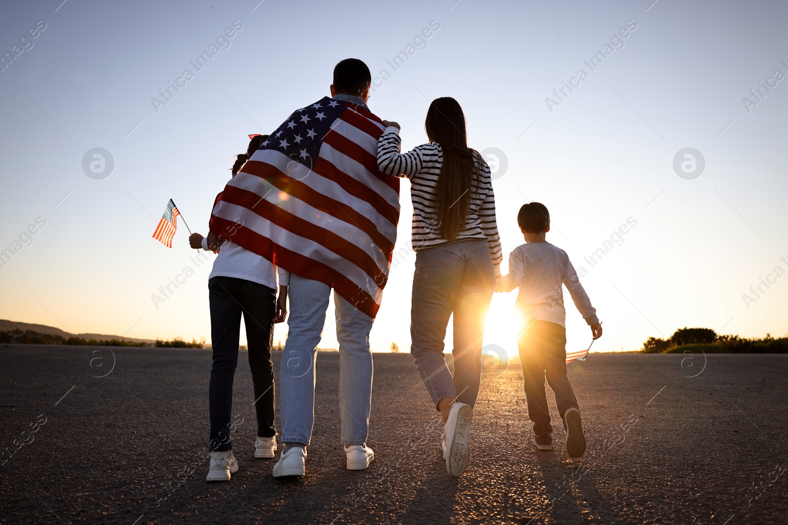 Photo of Family with flags of USA outdoors, back view