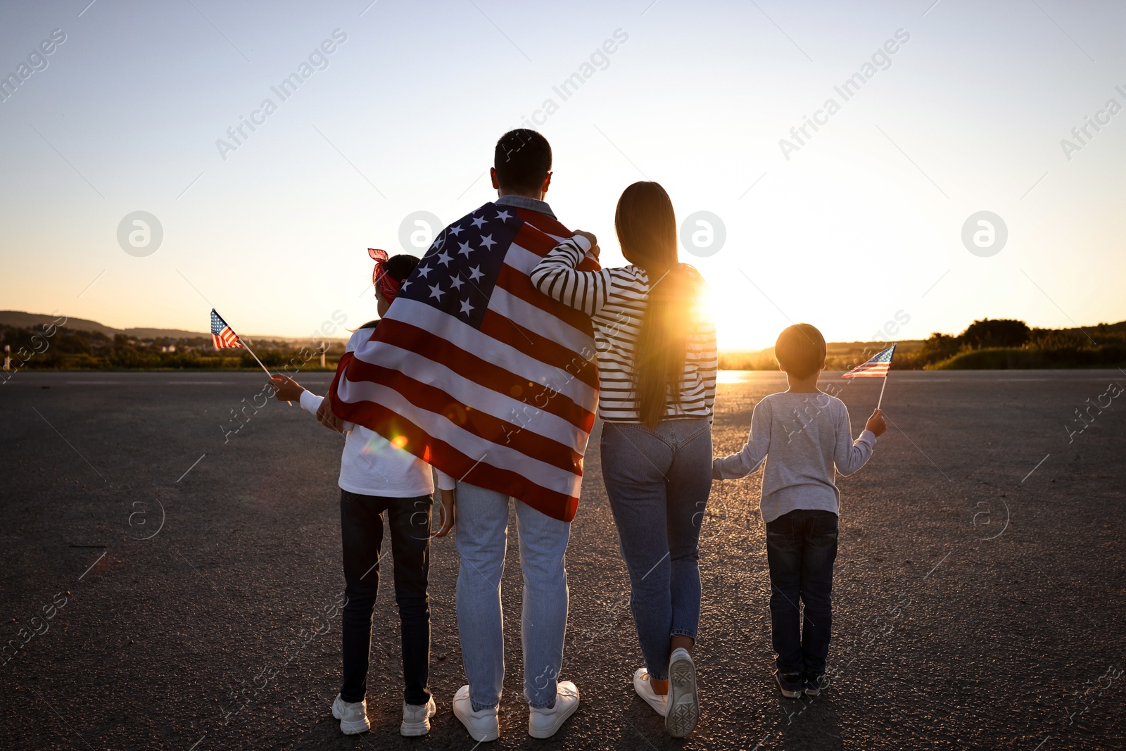 Photo of Family with flags of USA outdoors, back view