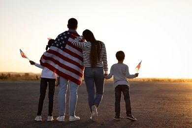 Family with flags of USA outdoors, back view