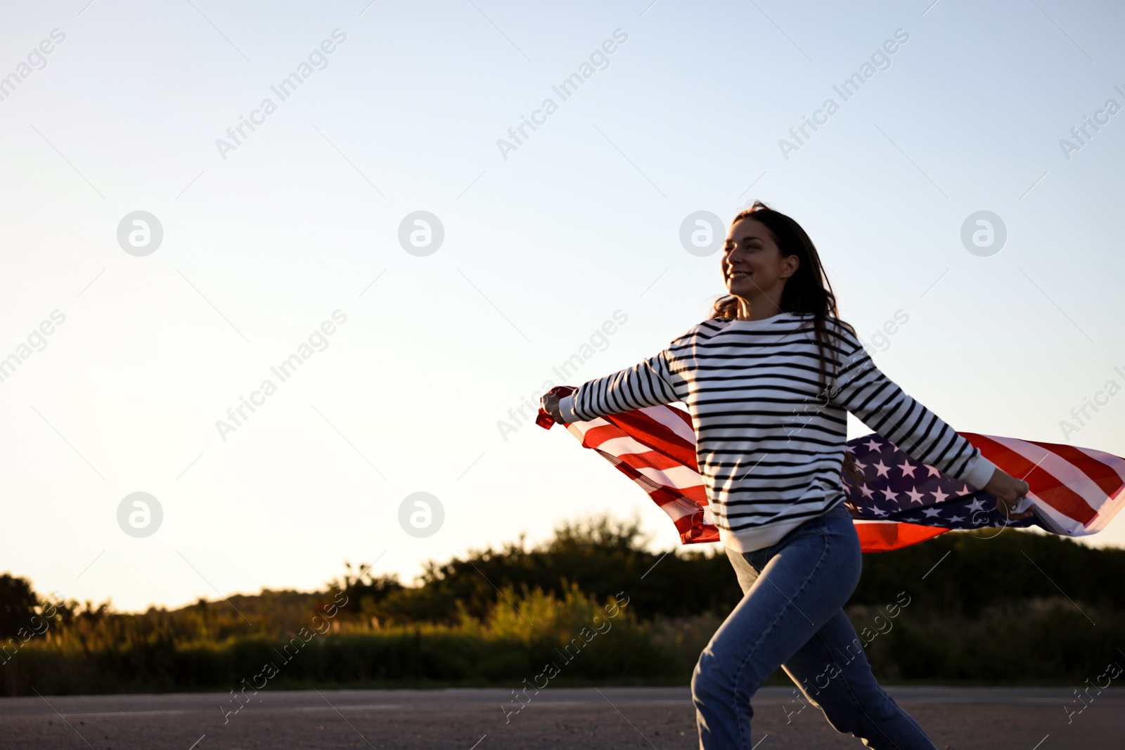 Photo of Happy woman with flag of USA running outdoors. Space for text