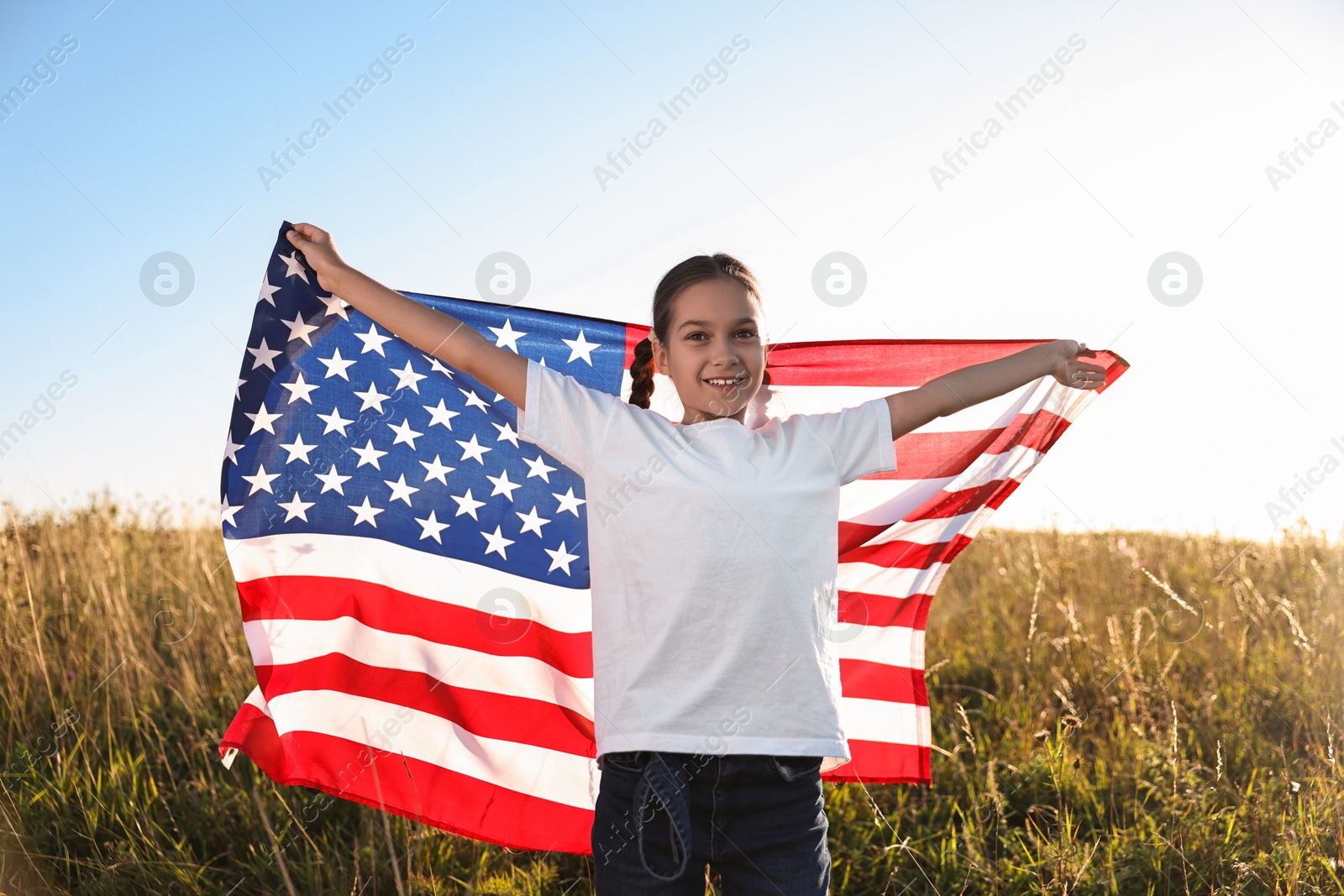 Photo of Happy girl with flag of USA outdoors