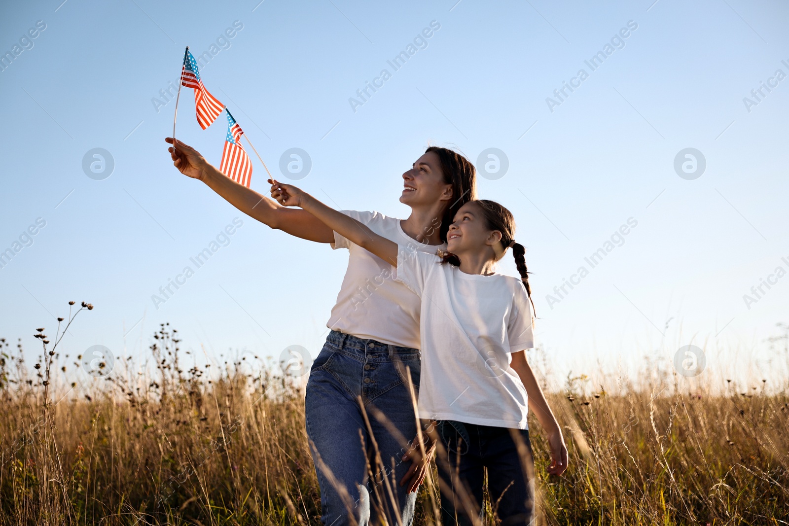 Photo of Happy mother and daughter with flags of USA outdoors, low angle view