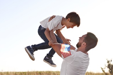 Happy father and son with flag of USA having fun outdoors