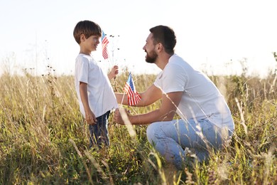 Photo of Happy father and son with flags of USA outdoors