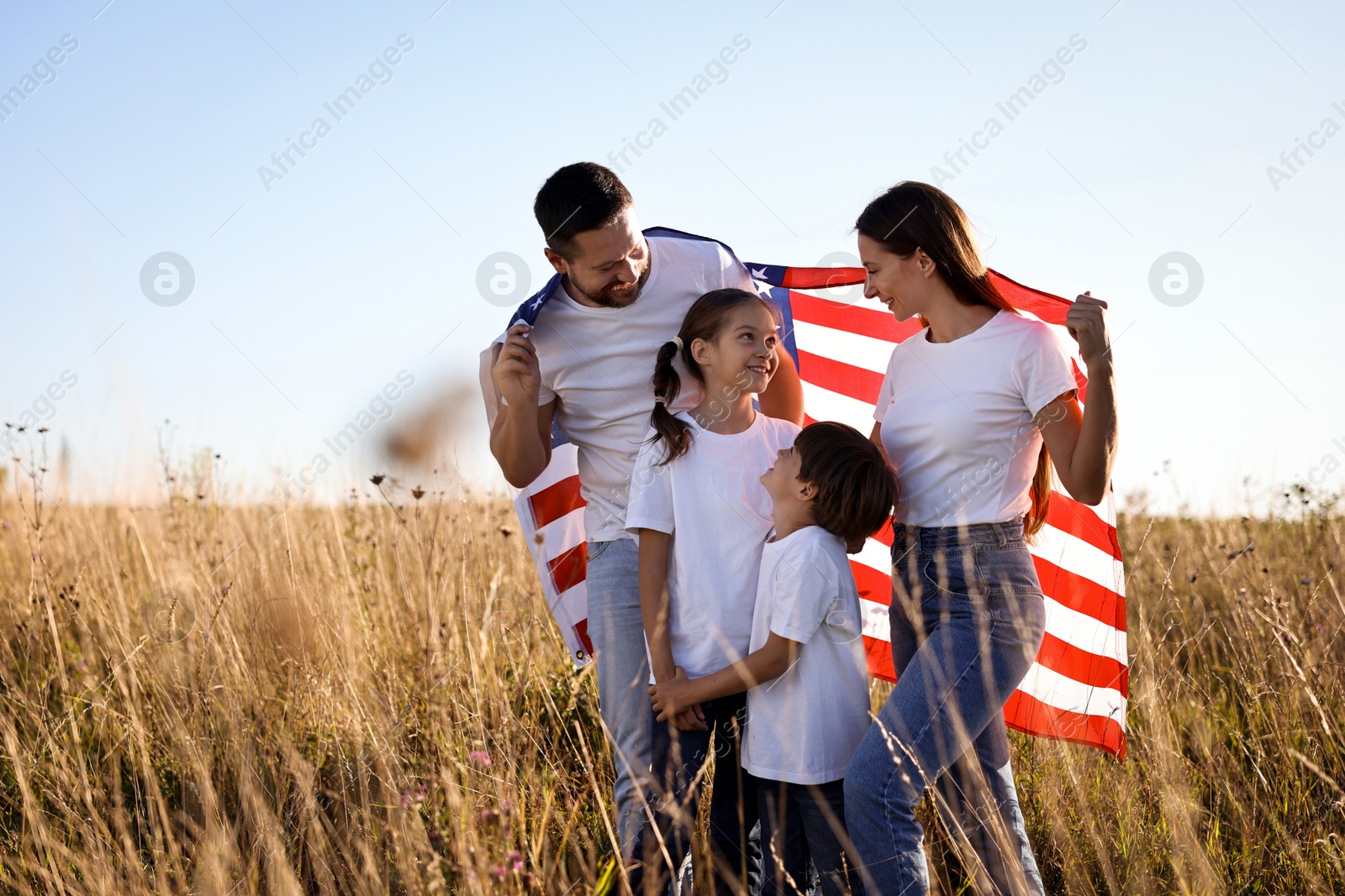 Photo of Happy family with flag of USA outdoors. Space for text