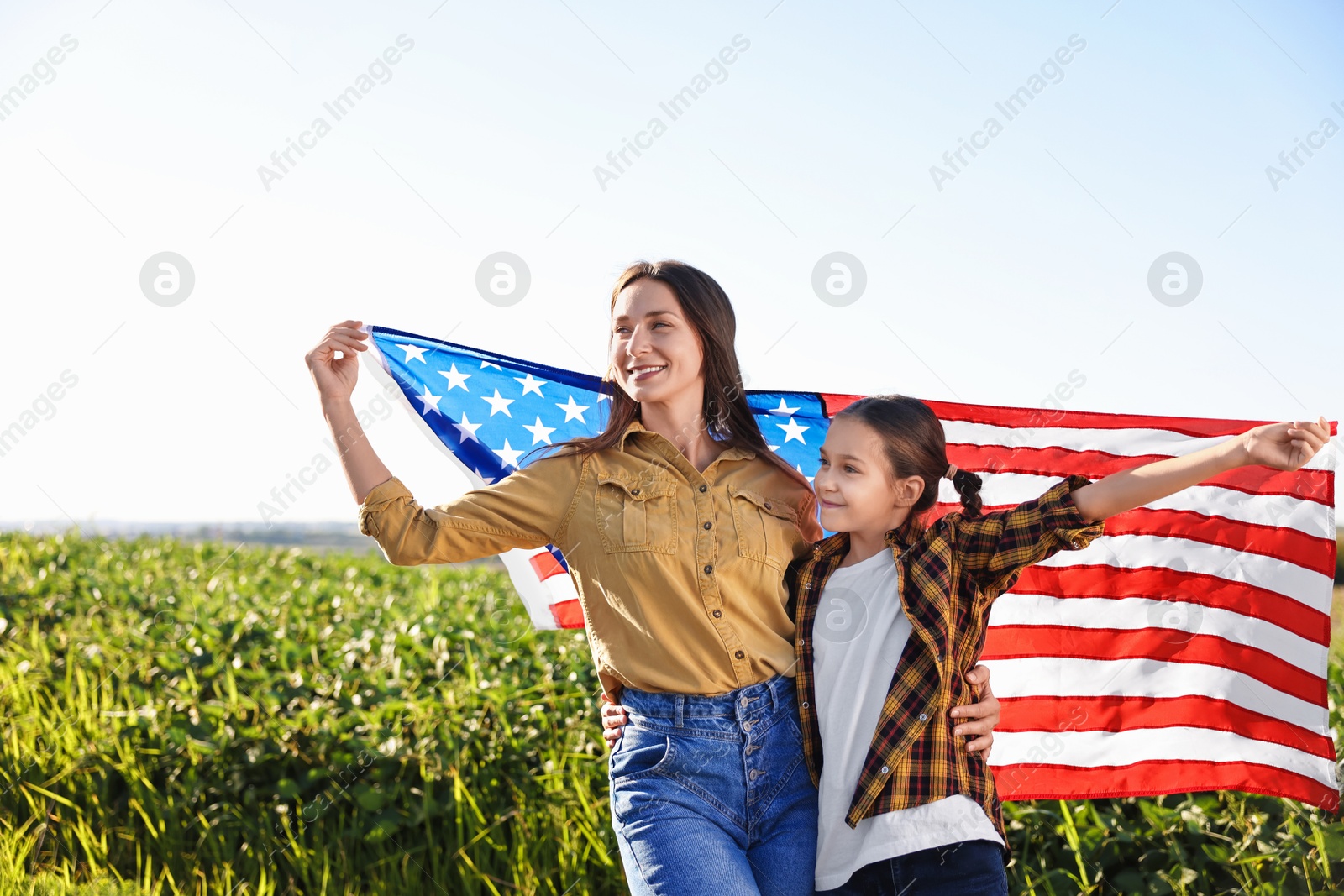 Photo of Happy mother and daughter with flag of USA outdoors. Space for text