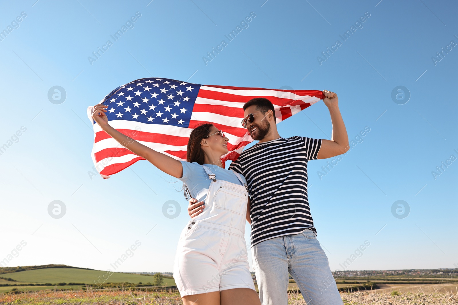 Photo of Happy couple with flag of USA outdoors, low angle view