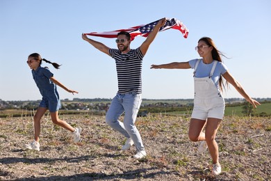 Happy family running with flag of USA outdoors