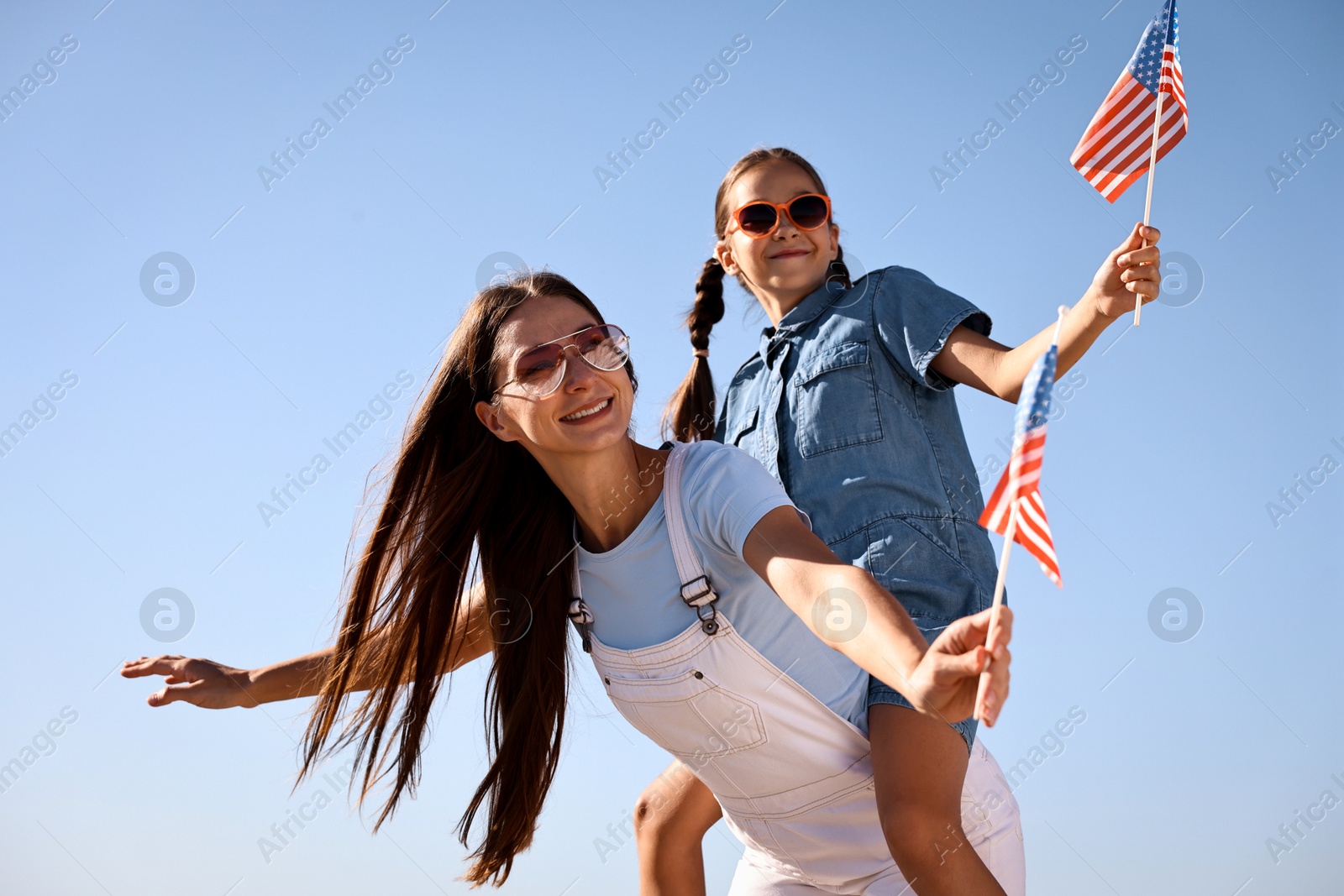 Photo of Happy mother and daughter with flags of USA outdoors