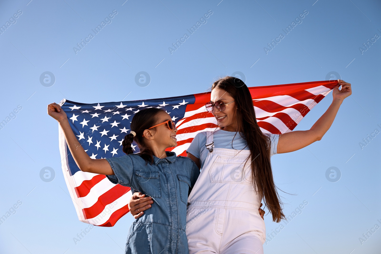 Photo of Happy mother and daughter with flag of USA outdoors