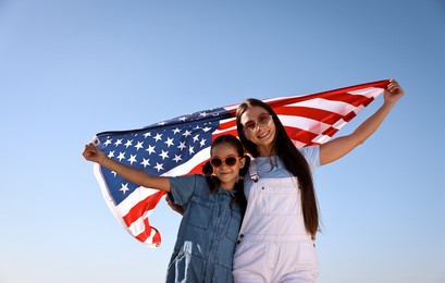 Photo of Happy mother and daughter with flag of USA outdoors