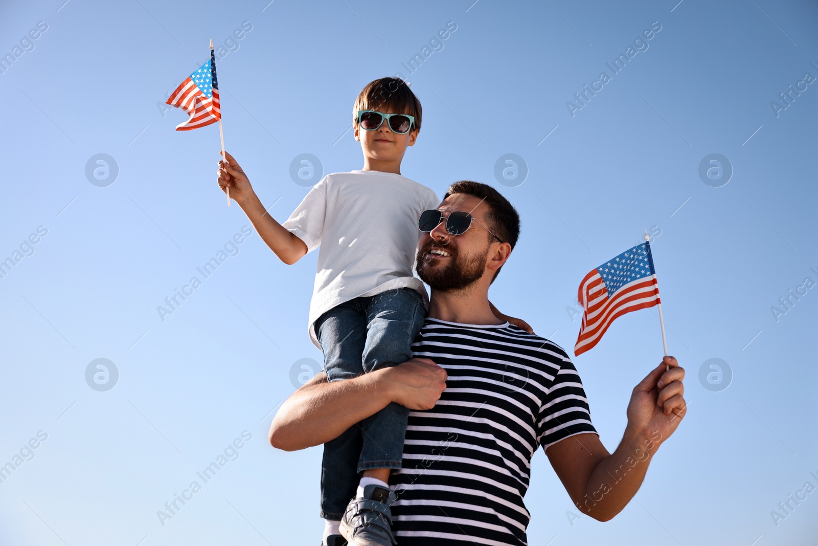 Photo of Happy father and son with flags of USA outdoors