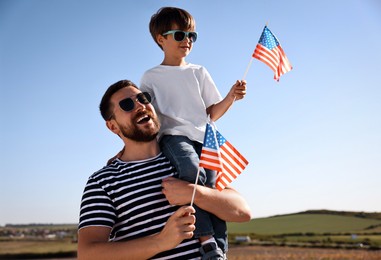 Photo of Happy father and son with flags of USA outdoors