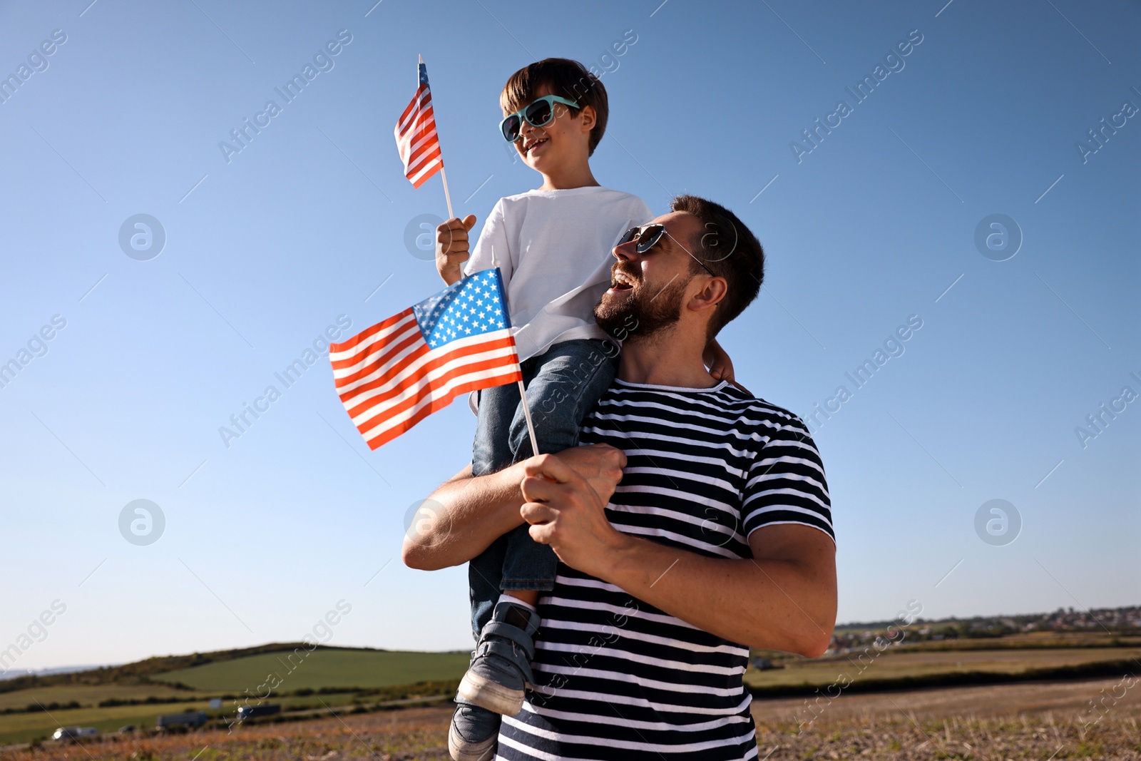 Photo of Happy father and son with flag of USA outdoors