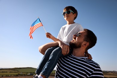 Photo of Happy father and son with flag of USA outdoors