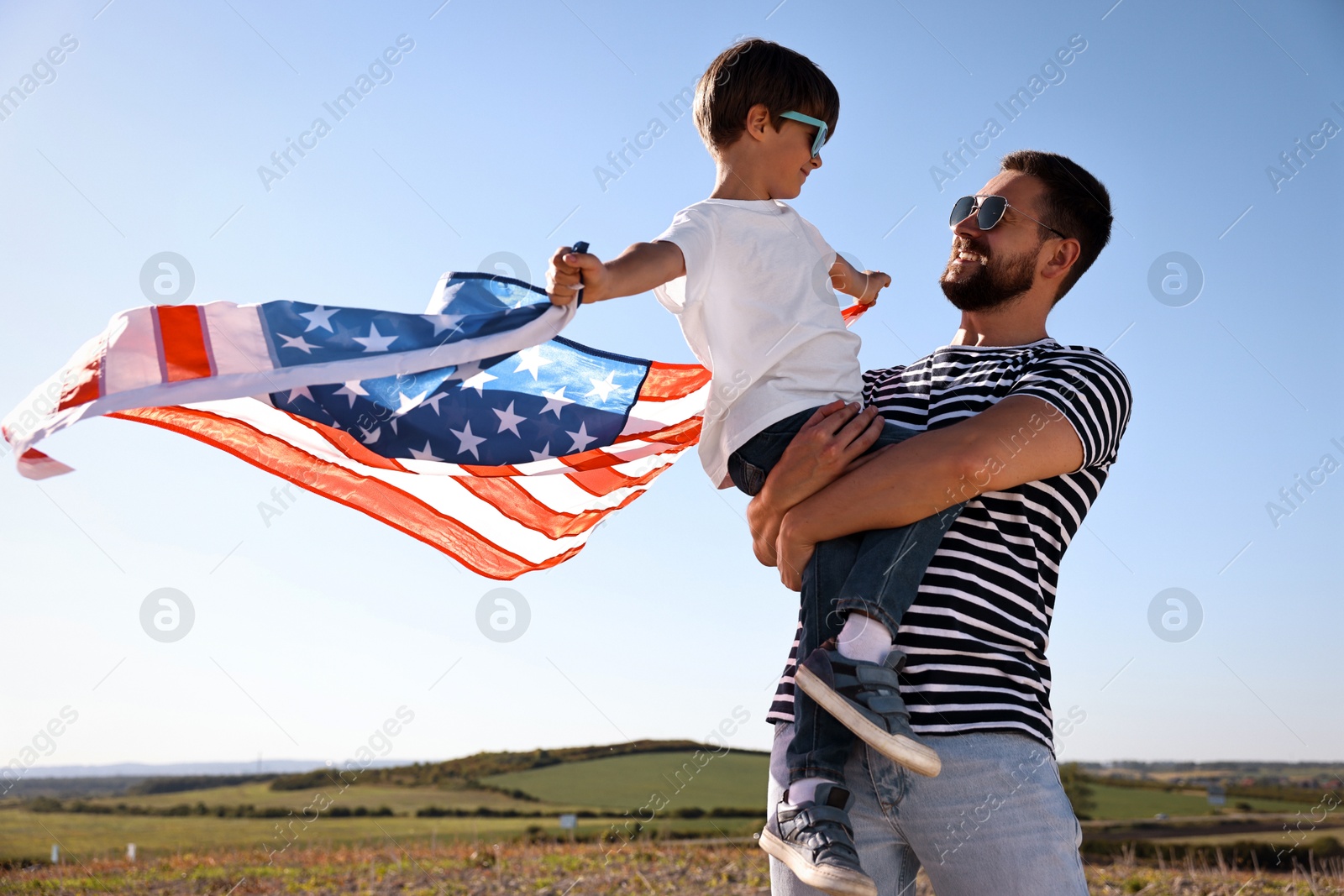 Photo of Happy father and son with flag of USA outdoors