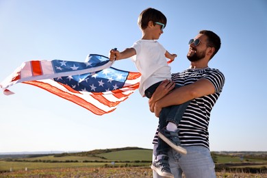 Happy father and son with flag of USA outdoors