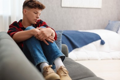 Photo of Loneliness concept. Sad teenage boy on sofa in room, space for text