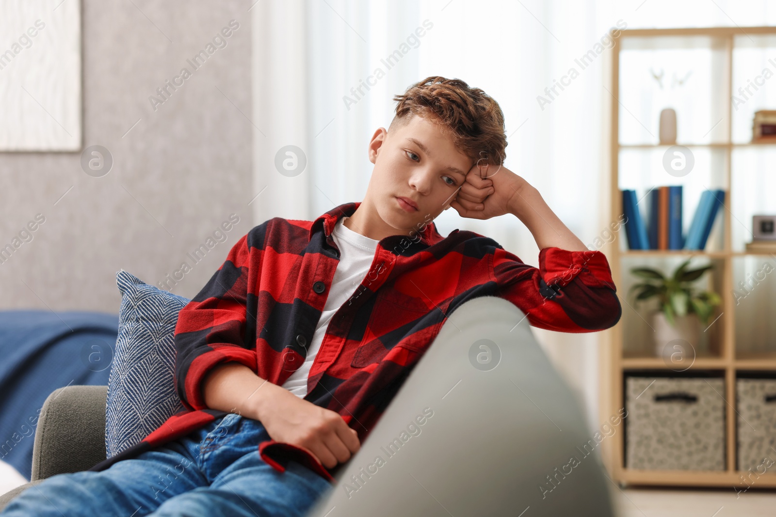 Photo of Loneliness concept. Sad teenage boy on sofa in room