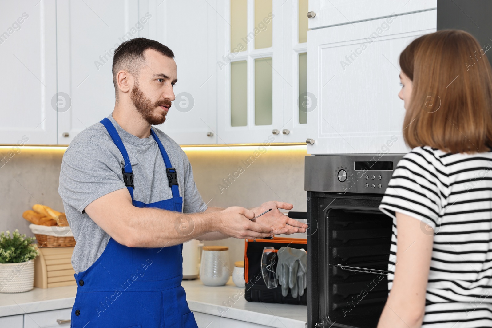 Photo of Repairman consulting woman near oven in kitchen