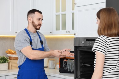 Repairman consulting woman near oven in kitchen