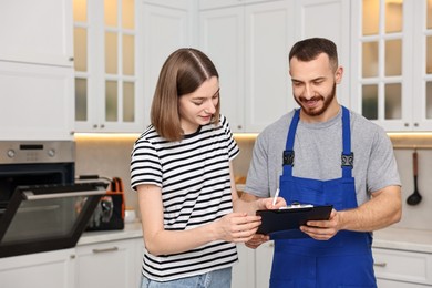 Woman and repairman signing documents near oven in kitchen