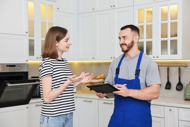 Photo of Woman talking with smiling repairman near oven in kitchen