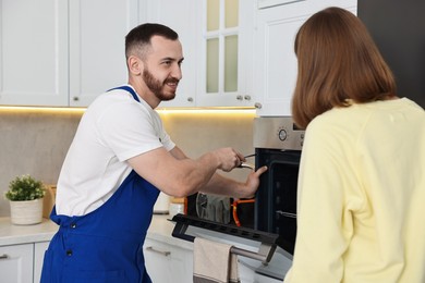 Smiling repairman consulting woman near oven in kitchen