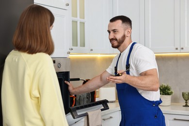 Photo of Smiling repairman consulting woman near oven in kitchen