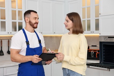 Photo of Woman and repairman signing documents near oven in kitchen