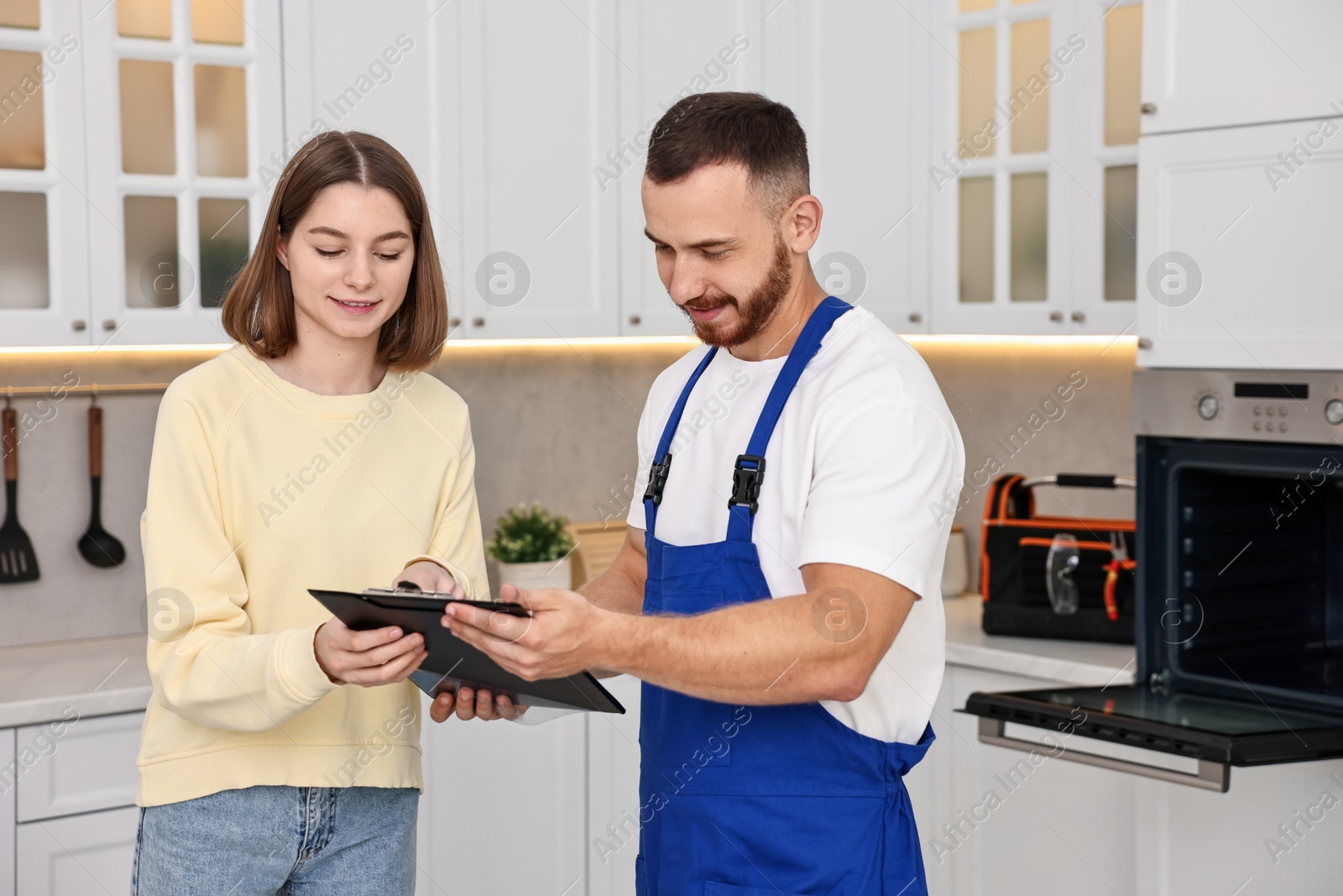 Photo of Woman and repairman signing documents near oven in kitchen