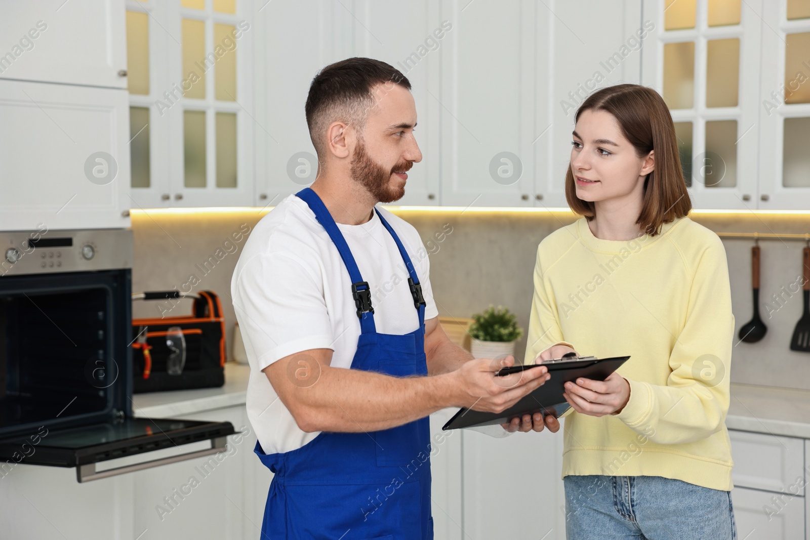 Photo of Woman and repairman signing documents near oven in kitchen