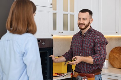 Photo of Smiling repairman consulting woman near oven in kitchen