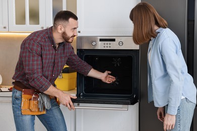 Smiling repairman consulting woman near oven in kitchen