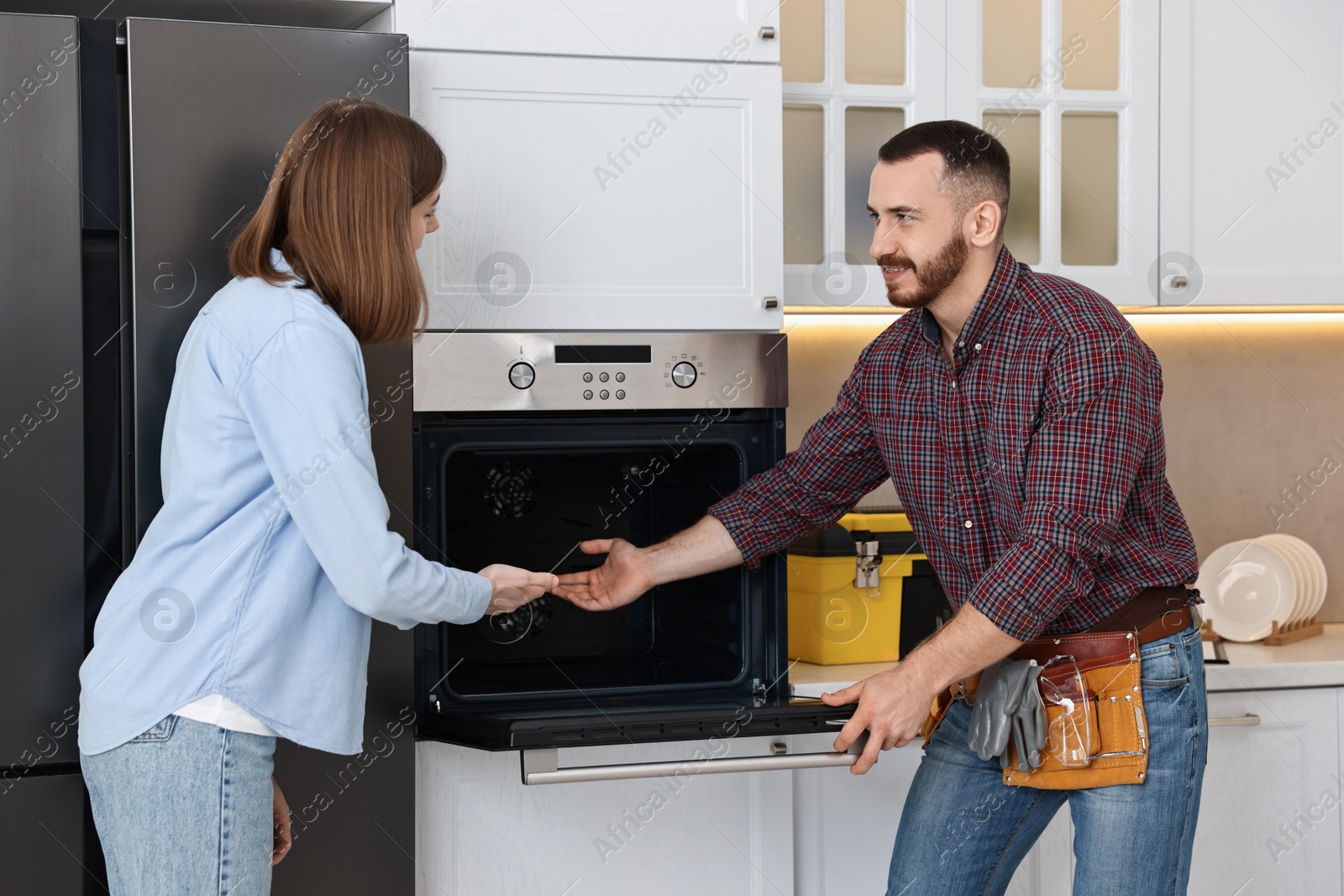 Photo of Smiling repairman consulting woman near oven in kitchen