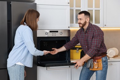 Smiling repairman consulting woman near oven in kitchen