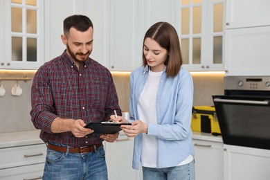 Photo of Woman and repairman signing documents near oven in kitchen