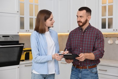 Woman and repairman signing documents near oven in kitchen