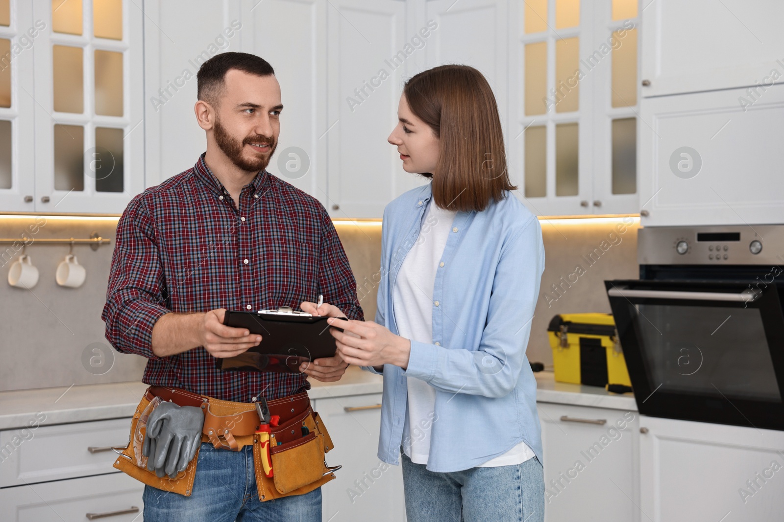 Photo of Woman and repairman signing documents near oven in kitchen