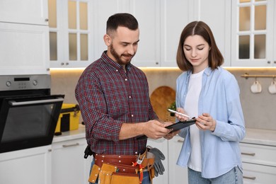 Woman and repairman signing documents near oven in kitchen