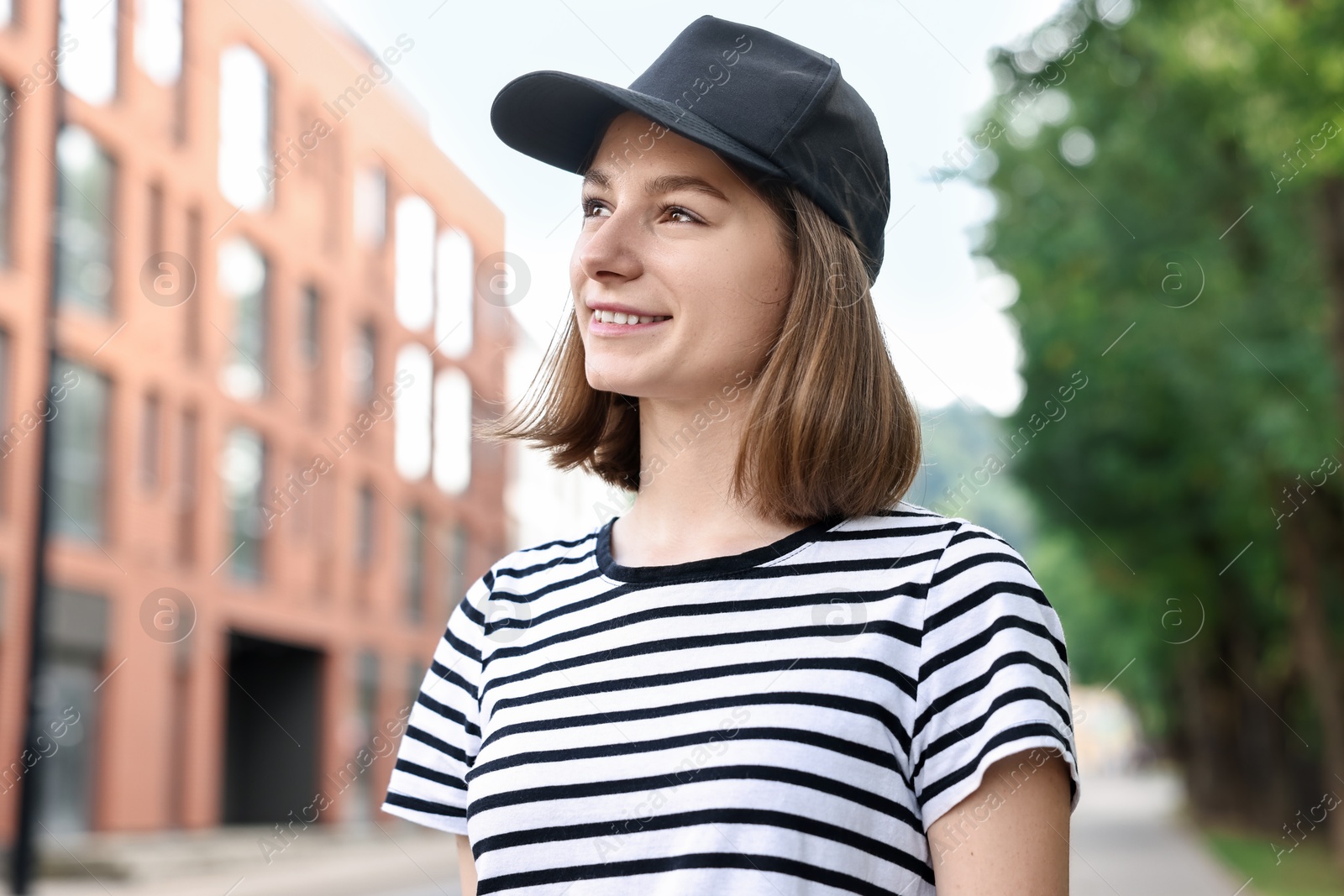 Photo of Portrait of smiling woman in baseball cap outdoors