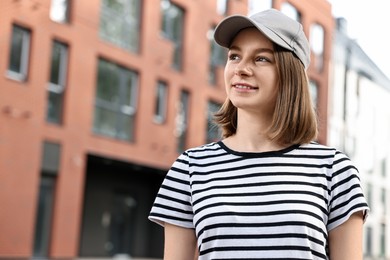 Photo of Portrait of smiling woman in baseball cap outdoors. Space for text