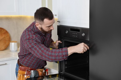 Professional repairman working with oven in kitchen