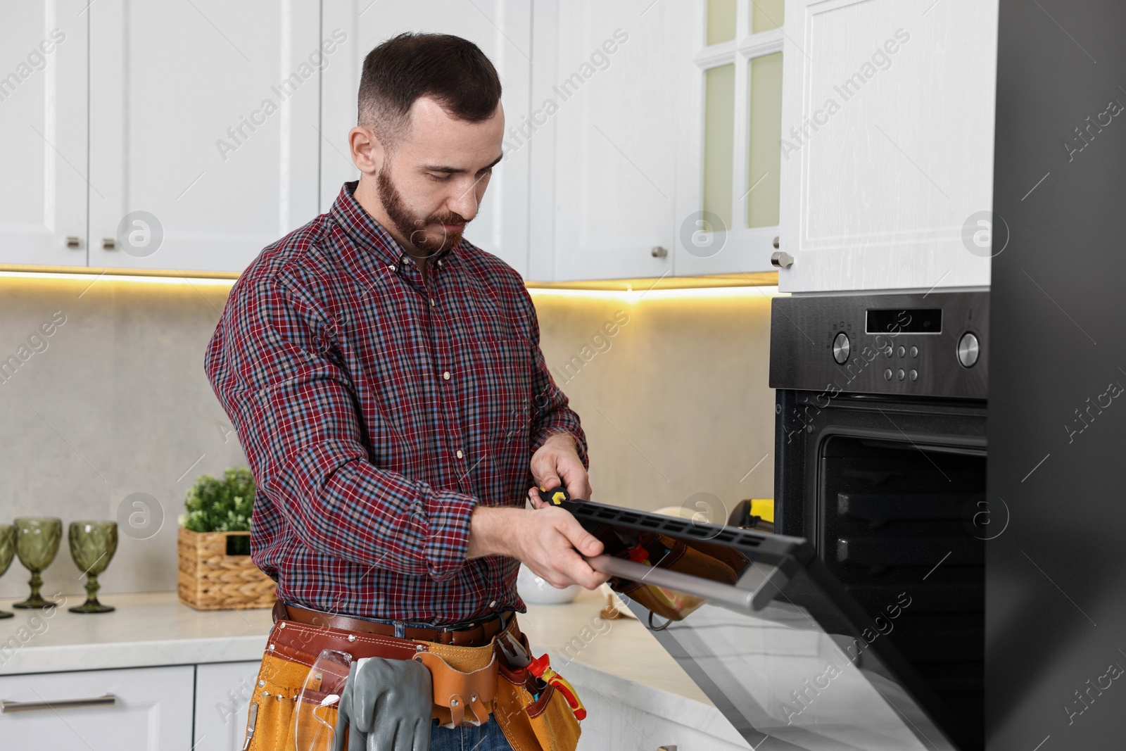 Photo of Professional repairman working with oven in kitchen