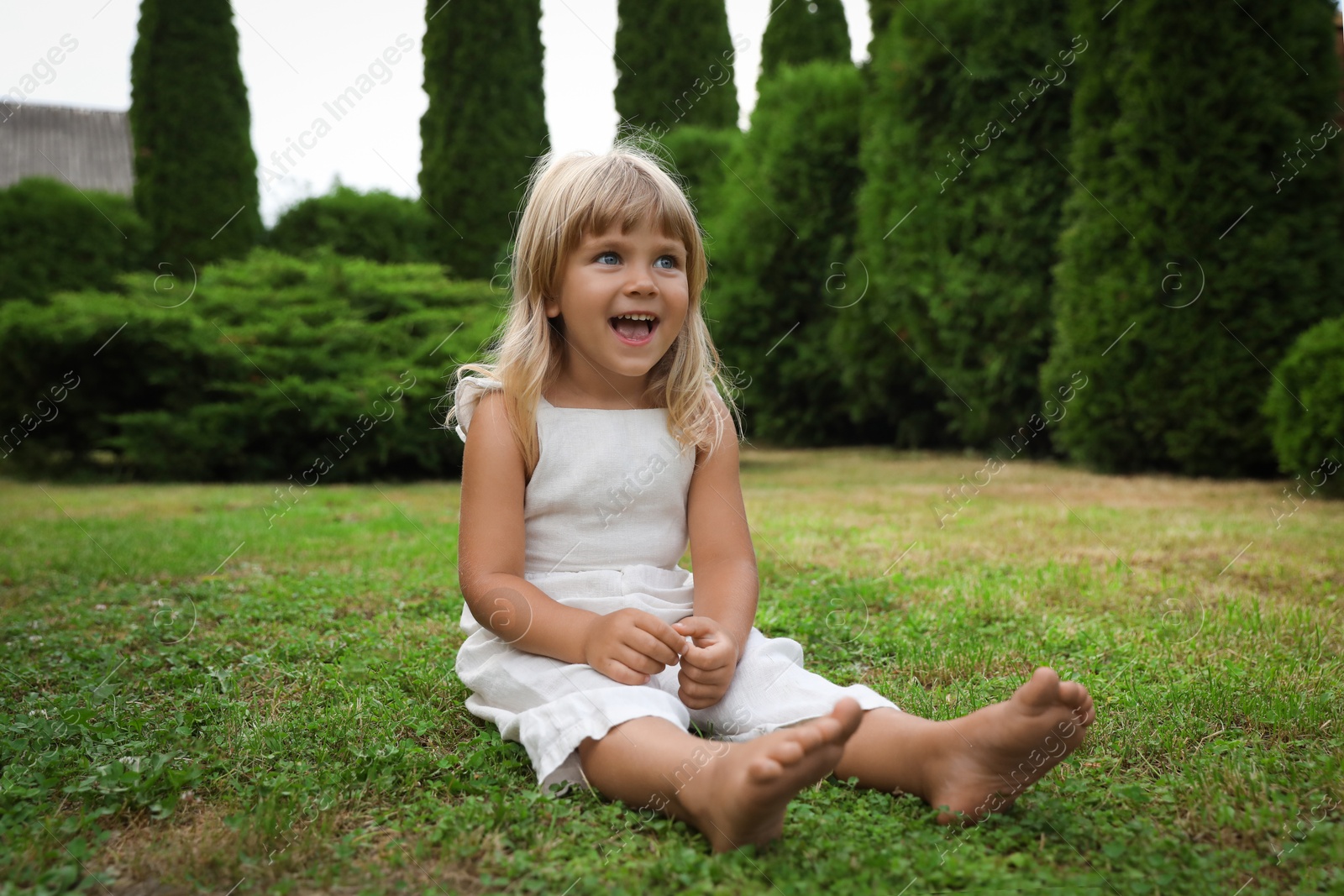 Photo of Barefoot little girl on green grass outdoors. Child enjoying beautiful nature