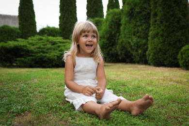 Barefoot little girl on green grass outdoors. Child enjoying beautiful nature