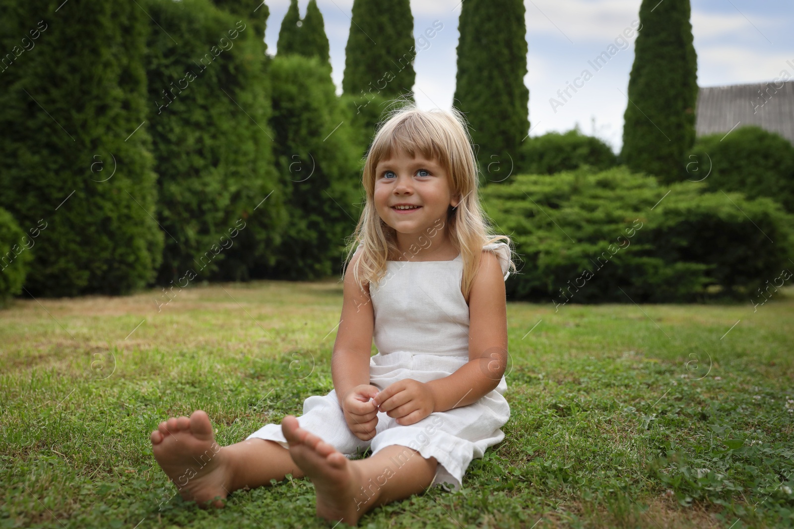 Photo of Barefoot little girl on green grass outdoors. Child enjoying beautiful nature