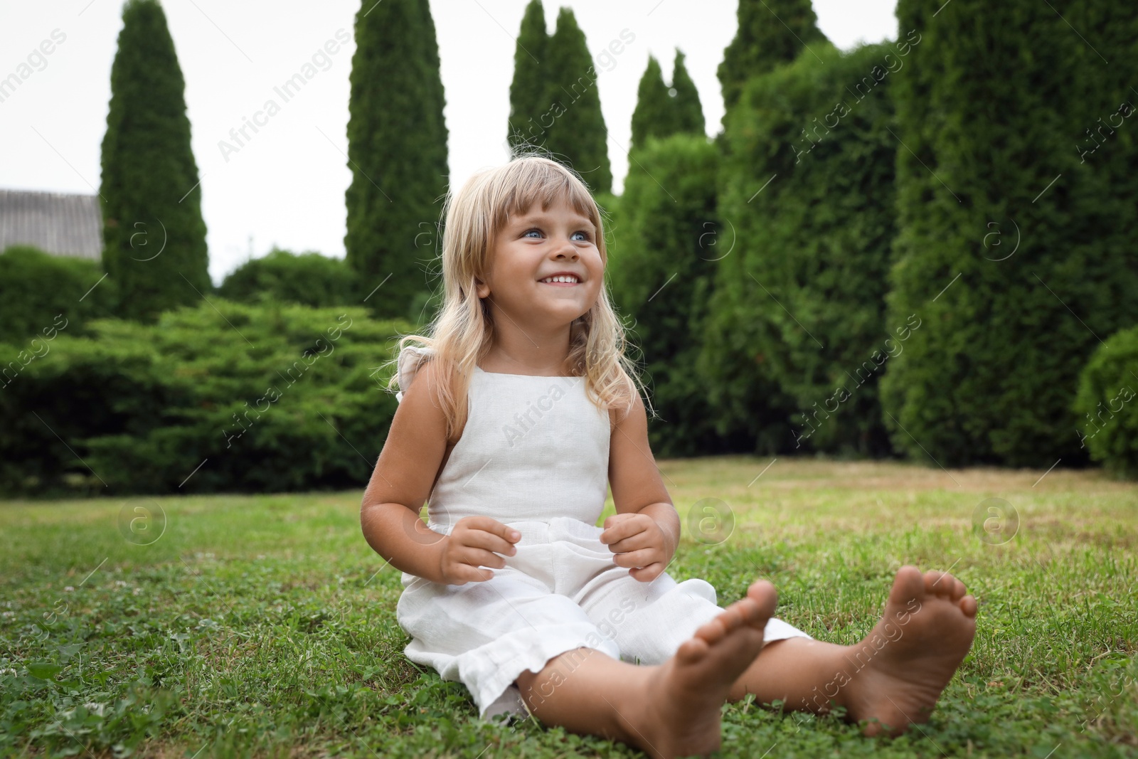 Photo of Barefoot little girl on green grass outdoors. Child enjoying beautiful nature