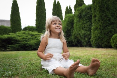 Barefoot little girl on green grass outdoors. Child enjoying beautiful nature